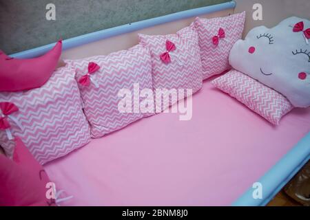 Cuscini rosa con diversi motivi si trovano in un lettino per bambini di albero blu . Presepe bianco e blu . Foto Stock