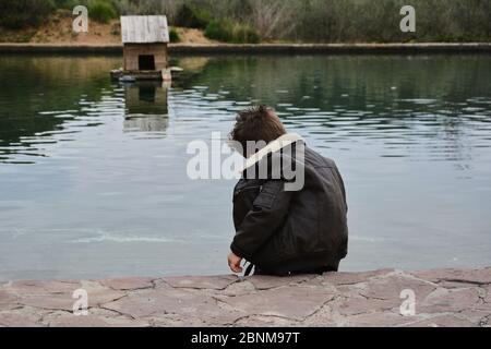 Ragazzo scuro guardando la zattera d'acqua con anatre, colori della natura Foto Stock