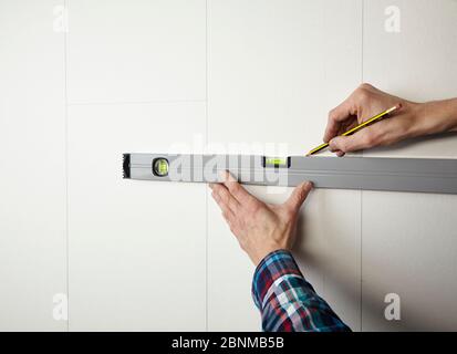 Progetto di parete DIY 02, produzione fai-da-te passo passo passo, varie aree turchesi colorate separate da strisce di legno bianco, passo 01: Contrassegnare le aree sulla parete con una matita e livella a bolla d'aria Foto Stock