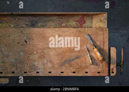 banco da lavoro in legno antico, fotografato graficamente dall'alto, pavimento di officina grigio scuro, con pochi utensili, ordinato, variante 4 di 5 Foto Stock