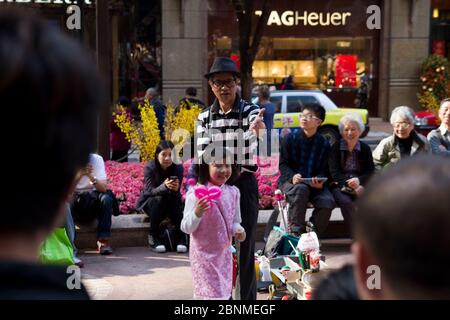 Artista di palloncino di strada con bambina in rosa a Hong Kong Foto Stock