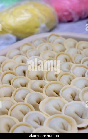 Pelmeni crudi o gnocchi con carne, fondo colorato di pasta Foto Stock