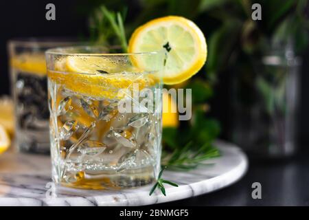 Limonata, cocktail mojito al limone, bevanda estiva fredda, ghiacciata e rinfrescante in bicchieri con fetta di limone su vassoio di marmo vista laterale. Spazio di copia. Foto Stock