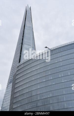 La cima dello Shard Building nel centro di Londra, Inghilterra, Regno Unito parzialmente oscurata da un altro edificio nella capitale Foto Stock