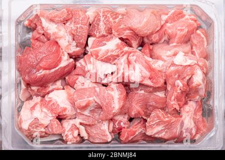 Pezzi di maiale crudo in contenitore di plastica. Fette di carne fresca, maiale dal negozio, mercato, vista dall'alto. Foto Stock