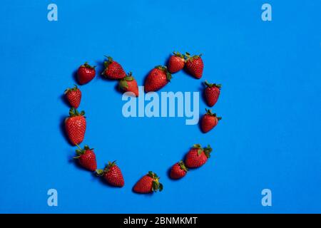 Cuore fatto di fragole su sfondo blu. Colori della natura Foto Stock