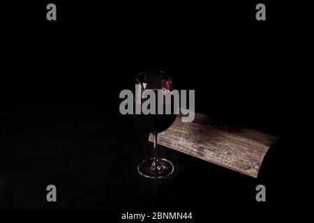 Bicchiere di vino rosso, accanto ad una piastrella, su sfondo nero Foto Stock