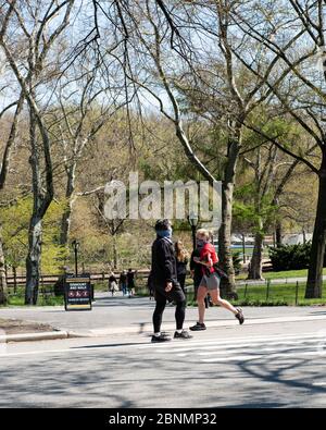 Persone che camminano a Central Park, New York, indossando maschere durante la pandemia. Foto Stock