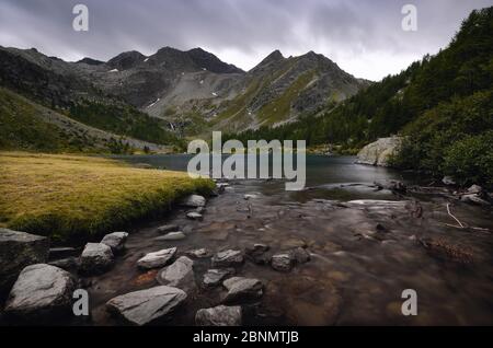 Cielo e acqua drammatici che scorrono in giornate buie sul Lac d’Arpy, bellissimo lago alpino vicino a Morgex (Valle d’Aosta, Italia) e al Monte Bianco Foto Stock