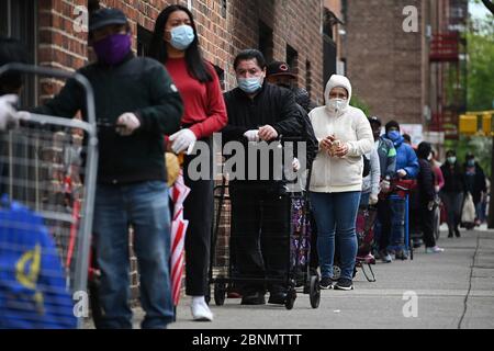 New York City, Stati Uniti. 15 maggio 2020. Le persone che indossano maschere per il focolaio di Coronavirus, aspettano in fila per ricevere assistenza alimentare alla Chiesa cattolica romana della parrocchia di Saint Bartholomew nel quartiere Elmhurst del quartiere di Queens, New York, 15 maggio 2020. Foto Stock