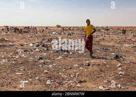 Disastro ecologico nel deserto del Sahara rifiuti e rifiuti accumulati intorno città africano ragazzo su palo di rifiuti Foto Stock