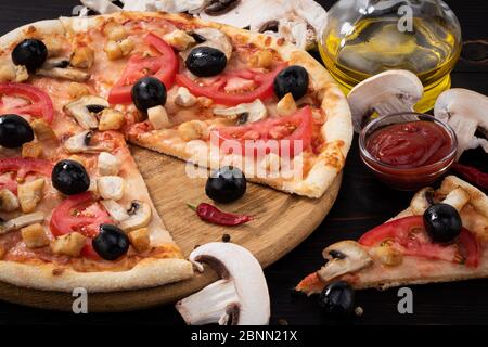 Pizza con pollo, funghi e olive su fondo ligneo. Foto Stock