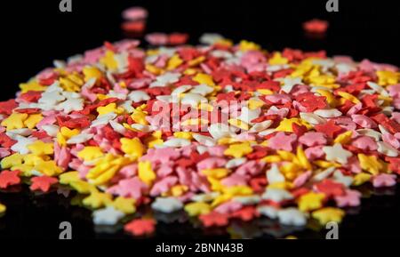 Caramelle multicolore sotto forma di stelle su sfondo nero Foto Stock