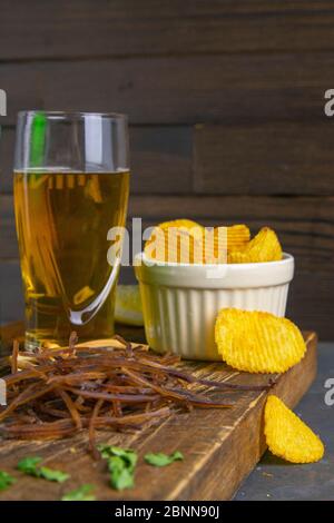 Squid ciottola scuro con birra, limone e patatine patatine su legno scuro. Snack a base di pesce con birra. Primo piano Foto Stock