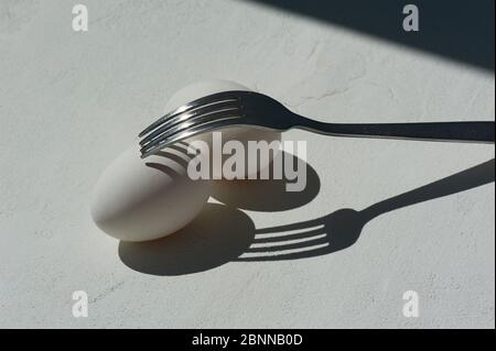 Uovo con ombra dal fork.Minimalism. Pasticceria da cucina, omelette. Facile. Ombre e luce. Foto Stock