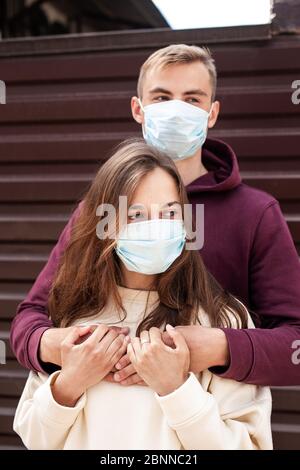 Giovane coppia spaventata abbracciando una maschera di protezione del viso in città dal nuovo Coronavirus Covid 19 Foto Stock