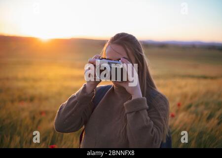 ragazza che fa una foto sul campo con la vecchia fotocamera Foto Stock