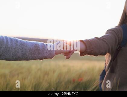 due donne che tengono le mani al tramonto sul campo Foto Stock