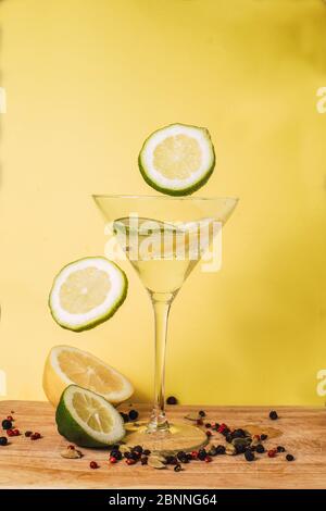 Fettine di limone e lime levitanti su fondo giallo. Foto Stock