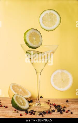Fettine di limone e lime levitanti su fondo giallo. Foto Stock