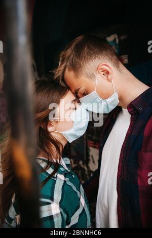 Coppia nell'amore, uomo e donna si baciano in maschera medica protettiva sul viso Foto Stock