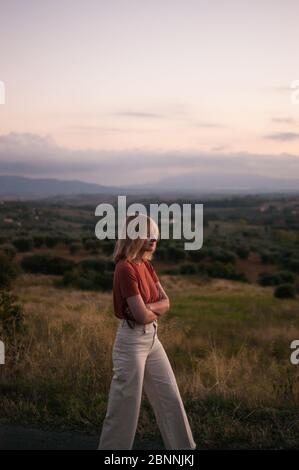 Giovane donna in Toscana paesaggio in Italia durante il tramonto con colori caldi Foto Stock