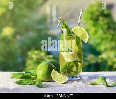 Cocktail di limonata o mojito con lime, cetriolo e menta, bevanda rinfrescante o bevanda fredda con ghiaccio, all'aperto. Acqua fredda detox con limone e carta Foto Stock