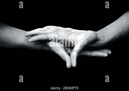 Primo piano di mani maschili che dimostrano Buddha Mudra su sfondo nero. Foto Stock