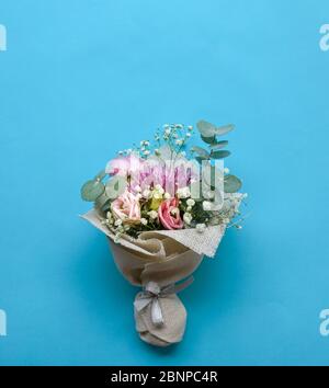 Bouquet di fiori a mano è composto da crisantemo, rose e foglie verdi su sfondo blu. Spazio di copia. Foto Stock