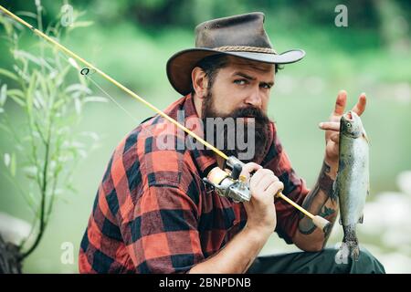 Ritratto dell'uomo in vacanza. Pesca sfondo. Avventure di pesca del mosca. Uomo vestito di pesca camicia con canna sul lago. Tempo del fine settimana. Pescatore uomo Foto Stock