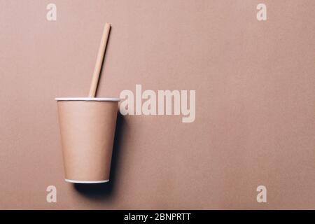 Tazza di caffè da asporto con cannuccia di bambù su fondo di carta naturale. Concetto di stile di vita sostenibile, senza sprechi. Disposizione piatta, vista dall'alto con spazio per la copia Foto Stock