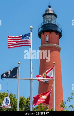 Lo storico faro di Ponce Inlet, completato nel 1887, a Ponce Inlet, Florida, con bandiere che sventolano sotto al Ponce Inlet Veterans Memorial. (STATI UNITI) Foto Stock
