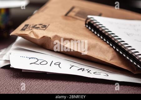 Una pila di documenti junky e posta con una busta che legge 2019 tasse Foto Stock