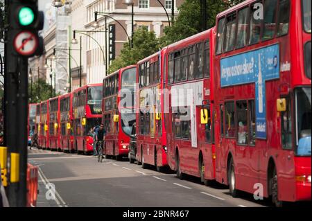 La congestione dei trasporti pubblici in Oxford Street a Londra con un ciclista che sorprende una lunga coda di autobus rossi. Foto Stock