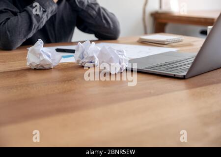 Una donna d'affari che lavora con sensazione di stress con carte avvitate e laptop sul tavolo in ufficio Foto Stock