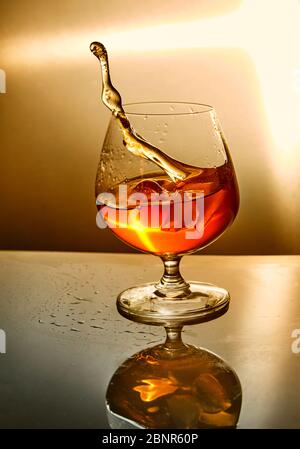 Bicchiere di whisky con un'onda su sfondo arancione. Bicchiere di whisky e schizzi simbolo design. Progettazione concettuale Foto Stock