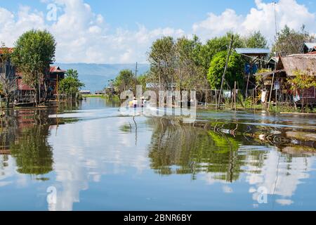 Inle Lake Myanmar - 2 novembre 2013; Inle Lake locali che si motorano in barca piccola su canale tra le case del villaggio galleggiante. Foto Stock