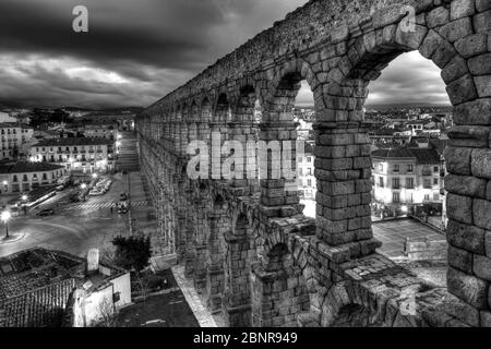 Spagna, Segovia: Acquedotto romano con Plaza de Azuguejo al tramonto, bianco e nero Foto Stock