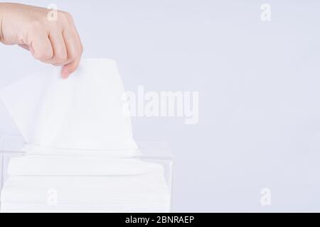 Mani femminili delicate che tirano una carta bianca fuori da una scatola di tessuto trasparente. Foto Stock