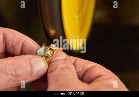 Produzione di gioielli. Gioielleria lucida un anello d'oro su una levigatrice in un laboratorio di gioielli. Foto Stock