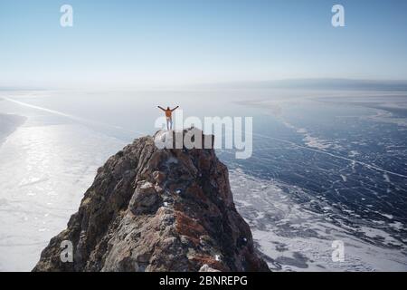 Lago Baikal in inverno. Uomo in piedi su una scogliera e guardando il lago ghiacciato Baikal. Il lago d'acqua dolce più profondo e grande. Isola di Olkhon, Russia, Siberia Foto Stock