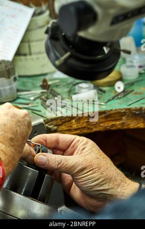 Produzione di gioielli. Il processo di fissaggio delle pietre con un fissatore, utilizzando un microscopio. Gioielli fare Foto Stock