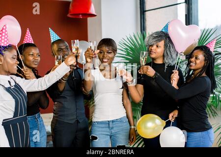 Gruppo di felici amici africani che bevono champagne e festeggiano il compleanno Foto Stock