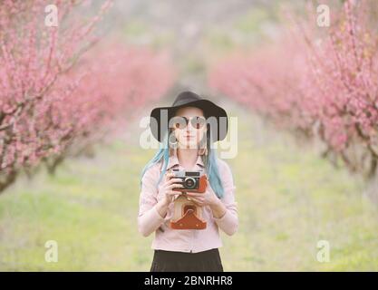 Ragazza con fotocamera in alberi in fiore. Foto Stock