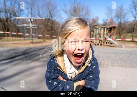 Il bambino si trova furiosamente di fronte a un parco giochi chiuso durante la crisi della corona del 2020 Foto Stock