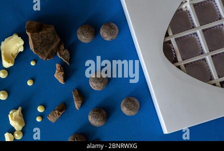 Pezzi di cioccolato su sfondo blu. Ingredienti per preparare dolci sani e deliziosi senza zucchero a casa. Cioccolato fatto in casa per San Valentino da Foto Stock