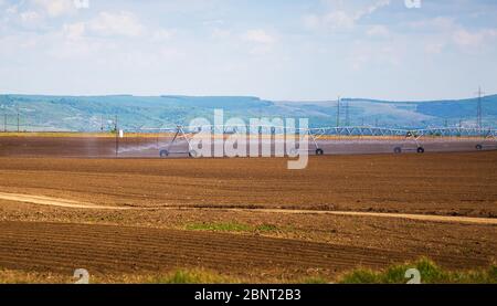 Sistema di irrigazione di campo. Un perno di irrigazione che innaffia un campo. Foto Stock