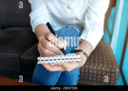 Immagine closeup di una donna che tiene e scrive su un notebook vuoto Foto Stock