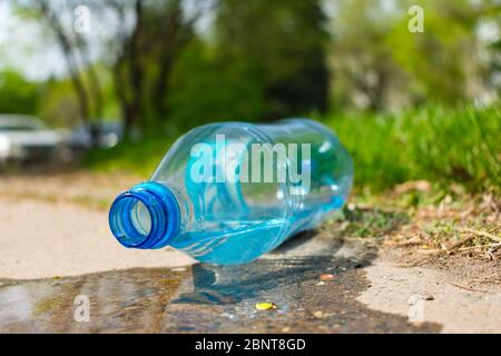 Inquinamento ambientale da bottiglie di plastica. Una bottiglia di plastica si trova sul pavimento in un parco Foto Stock