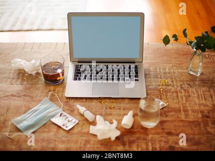 Da sopra vari farmaci e maschera medica posto sul tavolo vicino piante ramoscelli in vaso e laptop con schermo vuoto Foto Stock